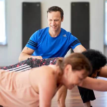 Personal Trainer Peter Neuwirth unterstützt eine Teilnehmerin bei einer Trainingsübung